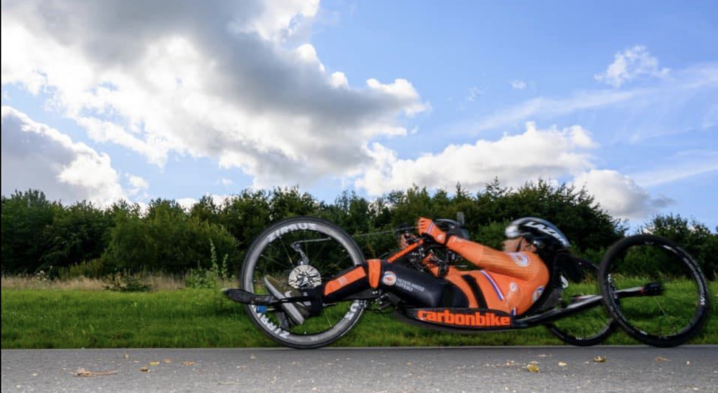 Carmen de personal trainer voor mensen met een beperking, terwijl ze traint met haar handbike in de buitenlucht.
